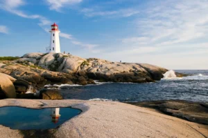 Ein Leuchtturm, stehend auf felsigem Untergrund an einer Küste, dient als Symbol für die Leitung und Sicherheit, die hochsensible Personen in ihrer Umgebung suchen. Die ruhigen Gewässer im Vordergrund, die den Leuchtturm und seinen leuchtenden roten Scheinwerfer spiegeln, unterstreichen die Bedeutung von innerem Frieden und Reflexion für Menschen mit Hochsensibilität. Die sanften Wellen, die gegen die Felsen schlagen, und der weite, offene Himmel bieten ein Bild der Harmonie und Stille, das hochsensiblen Personen hilft, ihre Umwelt intensiver wahrzunehmen und zu verarbeiten. Dieses idyllische Szenario spiegelt die Suche nach einem sicheren Hafen wider, der Schutz und Orientierung in einer überwältigenden Welt bietet.