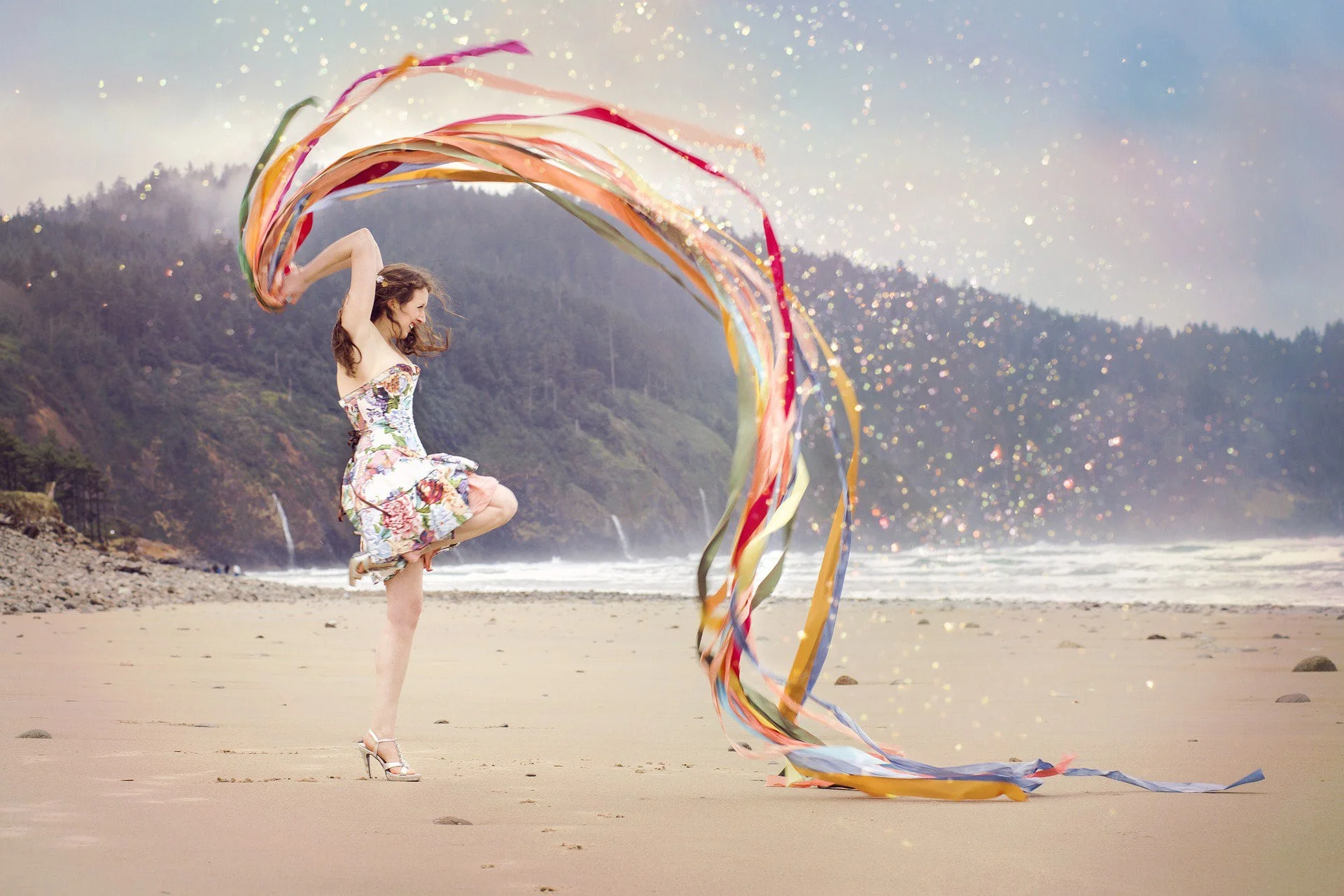 Eine Frau tanzt am Strand, umgeben von lebhaften, wirbelnden Bändern, die im Wind flattern. Diese Szene verkörpert Offenheit und Selbstfindung, eingefangen in einem Moment der Freiheit und des Einklangs mit der Natur, symbolisch für die Reise zu innerem Frieden und persönlicher Entfaltung.