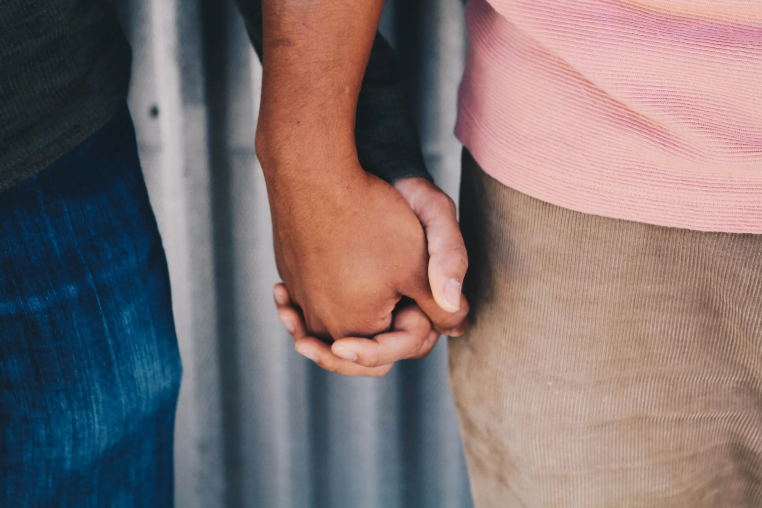 Zwei Menschen, sichtbar durch das Halten ihrer Hände, stehen Seite an Seite in einer Geste der Verbundenheit und Unterstützung. Ihre Hände, fest ineinander verschlungen, symbolisieren eine tiefe Bindung und das gegenseitige Vertrauen auf ihrem gemeinsamen Weg der Selbstfindung und Achtsamkeit. Diese einfache, aber kraftvolle Geste steht für die Bereitschaft, sich selbst und einander auf einer tieferen Ebene zu verstehen und zu akzeptieren. Es ist ein Moment der Stille und des bewussten Beisammenseins, der die Wichtigkeit der emotionalen Unterstützung und des Beistands auf der Reise zu persönlichem Wachstum und Selbstakzeptanz unterstreicht.