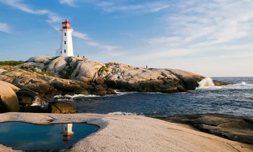 Ein Leuchtturm, stehend auf felsigem Untergrund an einer Küste, dient als Symbol für die Leitung und Sicherheit, die hochsensible Personen in ihrer Umgebung suchen. Die ruhigen Gewässer im Vordergrund, die den Leuchtturm und seinen leuchtenden roten Scheinwerfer spiegeln, unterstreichen die Bedeutung von innerem Frieden und Reflexion für Menschen mit Hochsensibilität. Die sanften Wellen, die gegen die Felsen schlagen, und der weite, offene Himmel bieten ein Bild der Harmonie und Stille, das hochsensiblen Personen hilft, ihre Umwelt intensiver wahrzunehmen und zu verarbeiten. Dieses idyllische Szenario spiegelt die Suche nach einem sicheren Hafen wider, der Schutz und Orientierung in einer überwältigenden Welt bietet.