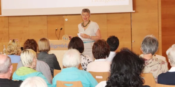 Eine Referentin spricht vor einem aufmerksamen Publikum bei einer Weiterbildungsveranstaltung in der Akademie Heiligenfeld. Der gut besuchte Seminarraum unterstreicht das Engagement der Teilnehmenden für ihre persönliche und berufliche Fortbildung.