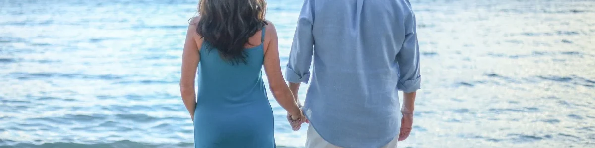 Meditationen-fuer-zwei Ein Paar steht Hand in Hand am Strand, blickt gemeinsam auf das weite Meer hinaus. Sie sind von der Ruhe des Wassers und dem sanften Rauschen der Wellen umgeben, ein Symbol für tiefe Kommunikation und starke Verbindung in ihrer Beziehung. Die harmonische Szene spiegelt das gegenseitige Verständnis und die Unterstützung wider, die sie füreinander empfinden, während sie gemeinsam in die Zukunft schauen. Dieser Moment der Stille und Einheit am Meer unterstreicht die Bedeutung von nonverbaler Kommunikation und der emotionalen Bindung, die das Fundament jeder starken Beziehung bildet.